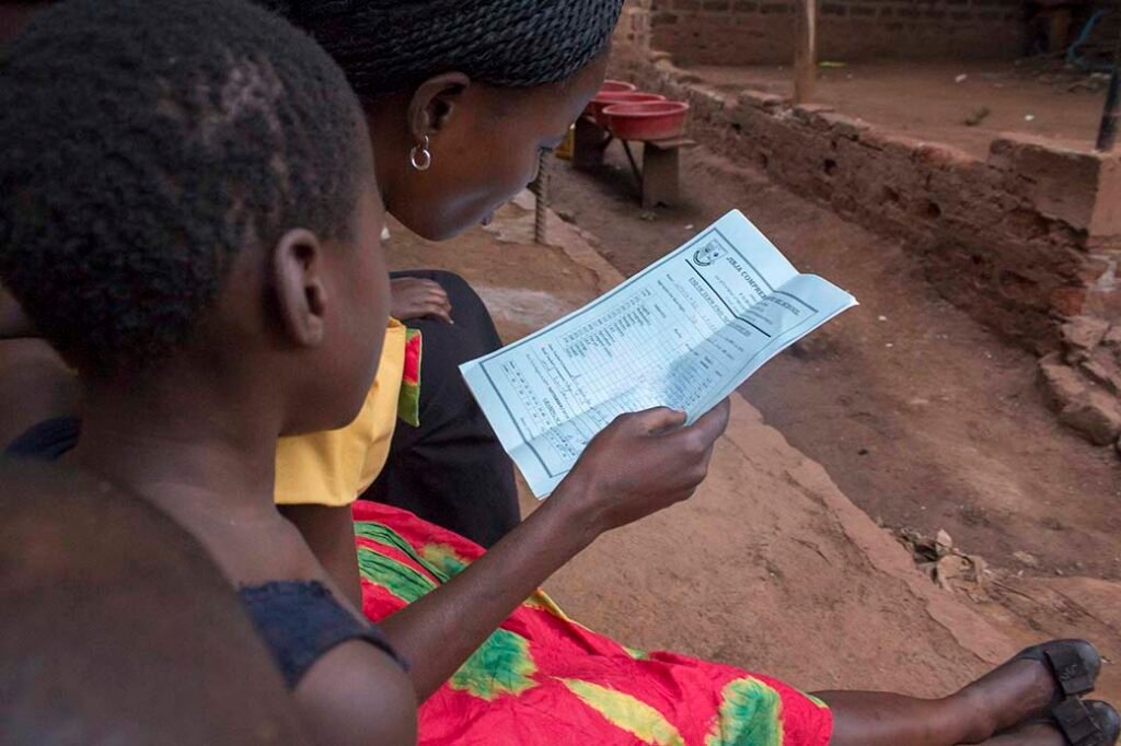Annet-looks-through-her-daughter_s-report-catrrd-from-school-in-jinjauganda